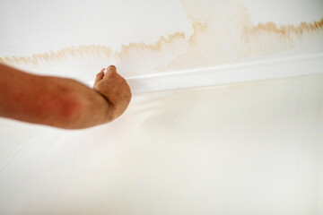 painting over red streaks after a pipe leak on the ceiling with white paint renovation