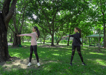 Asian woman in sportswear stretching and warming up before morning jogging. Sports training, jogging in city park.