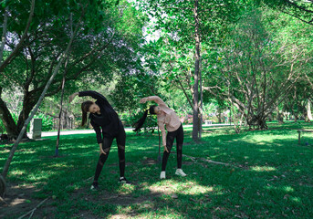 Asian woman in sportswear stretching and warming up before morning jogging. Sports training, jogging in city park.