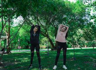 Asian woman in sportswear stretching and warming up before morning jogging. Sports training, jogging in city park.