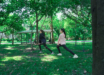 Asian woman in sportswear stretching and warming up before morning jogging. Sports training, jogging in city park.