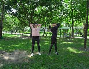 Asian woman in sportswear stretching and warming up before morning jogging. Sports training, jogging in city park.