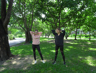 Asian woman in sportswear stretching and warming up before morning jogging. Sports training, jogging in city park.