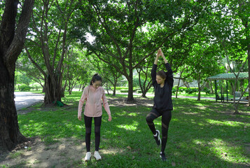 Asian woman in sportswear stretching and warming up before morning jogging. Sports training, jogging in city park.