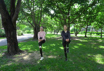 Asian woman in sportswear stretching and warming up before morning jogging. Sports training, jogging in city park.