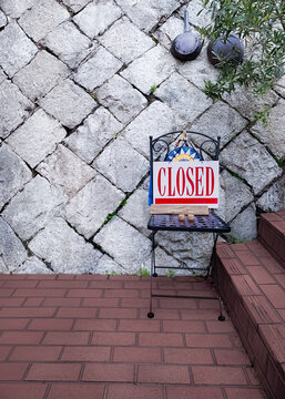 "CLOSED" sign board on a chair at an Italian restaurant