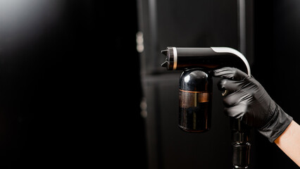 Close-up of instant tanning equipment in the hands of a master. Gun spraying paint for leather...