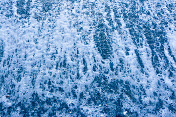 Close-up of whitewater rapids texture: The chaotic and bubbly texture of water rushing over rocks,...