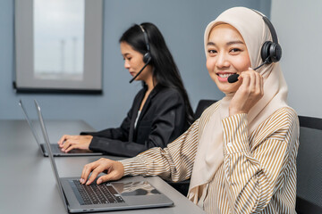 Young adult muslim women in headsets providing customer support in office. Friendly call center...