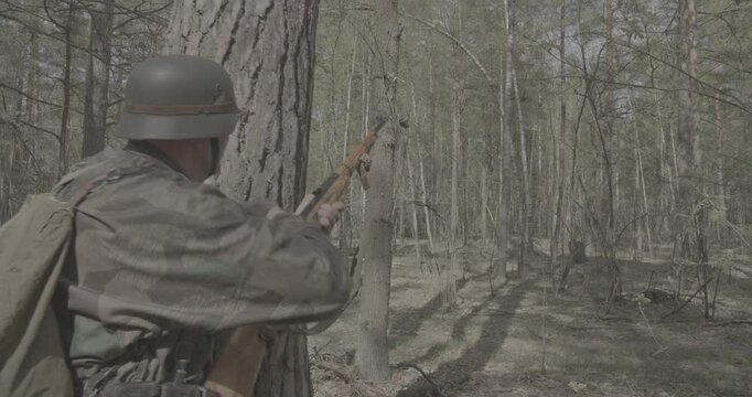 Reenactor Dressed As German Infantry Soldier Shoots From Rifle Carabine Mauser 98k. Weapon Jammed. War Ambush In Forest. Wermacht Military Uniform. Reenactment Combat. Reload And Shooting From Rifle
