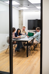 Group of young professionals working together on laptops and documents, sharing ideas and...