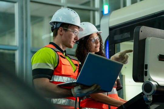 Two people are looking at a laptop computer. Concept of Industry 4.0 with diverse engineers collaborating on automation technology.