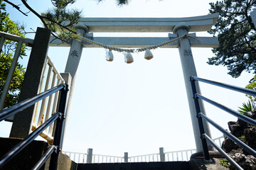 Torii gate to the entrance of a Japanese Shinto temple with sunlight shining through it