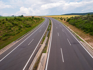 Empty highway D1 near Spišský Hrhov, Slovakia. Divided lanes in rural landscape with fields and forest in the background. View from above.