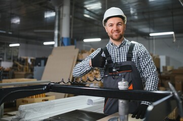 Carpenter gesturing thumbs up near cnc machine in furniture factory