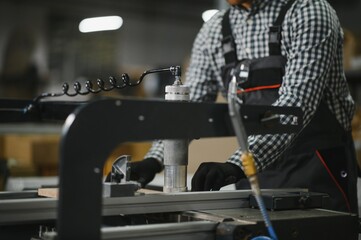 Carpenter using pneumatic press assembling wooden furniture in factory
