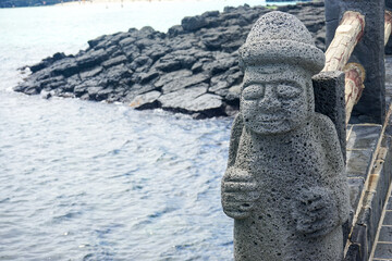 Close up view of a stone grandfather (Dol hareubang) volcanic rock statue at Hamdeok Beach on Jeju Island, South Korea