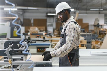 Carpenter operating woodworking machine in furniture factory