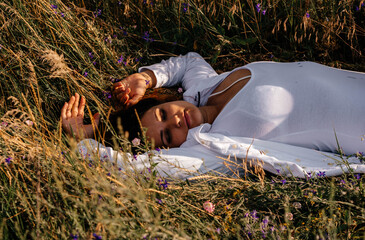 Brunette resting lying in a field on the grass. Meditation in nature. Interaction with nature....