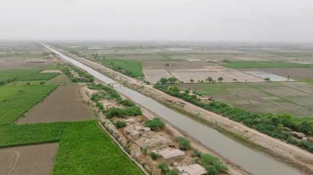 Drone shot of long canal running through the village near Badin in Sind, Pakistan. Natural landscape.