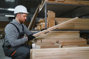 Skilled worker inspecting wood in furniture factory