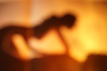 Silhouettes of a man and a woman making love. Blurred abstract background. An orange shade.