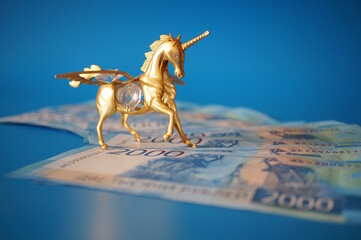 Unicorn figurine and paper bills on a blue background. Russian rubles.
