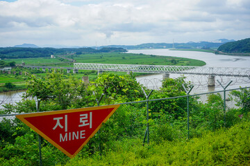 Looking towards South Korea from inside the Korean DMZ, behind a barbed wire fence and replica land mine warning sign in Paju, Gyeonggi-do, South Korea
