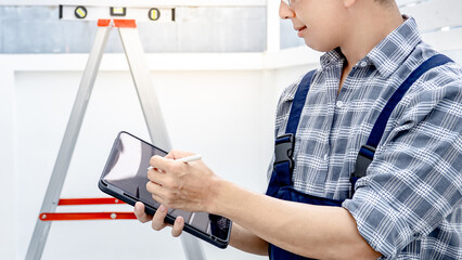 Building inspector man in workwear using digital tablet checking for the process of house project....