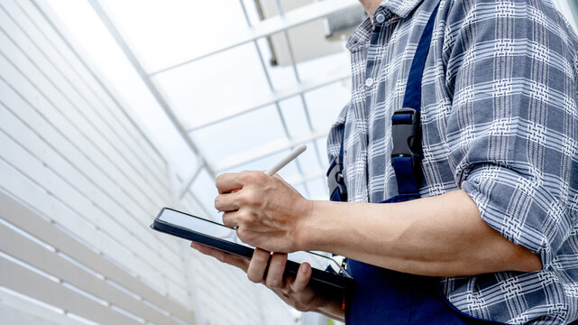 Professional building inspector man using digital tablet checking for site survey. Asian male engineer or architect inspecting wall and roof structure at construction site