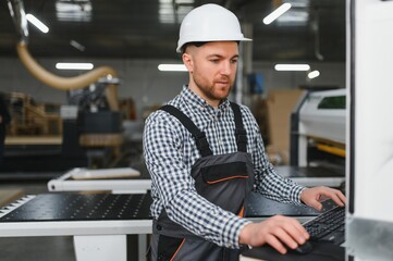 Carpenter operating cnc machine in furniture factory