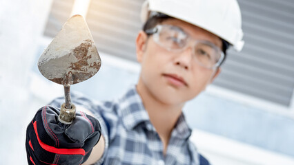 Plastering work tool. Asian man worker wearing protective safety helmet, goggles and gloves holding...