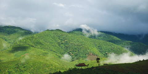 Rainbow over the greenery mountains and wooden cabin