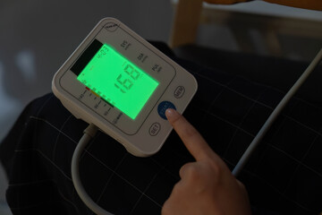 Health Monitoring. Individual using digital blood pressure monitor at home.