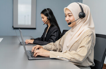 Young adult muslim women in headsets providing customer support in office. Friendly call center...