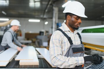 Furniture factory workers operating cnc machine for sofa production