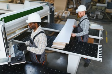 Furniture factory workers operating cnc machine for sofa production