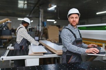 Furniture factory workers operating cnc machine for sofa production
