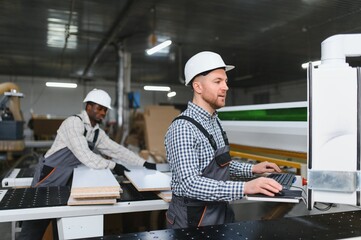 Furniture factory workers operating cnc machine for sofa production