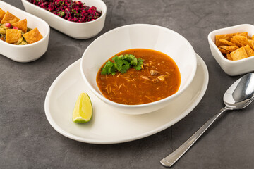 Spicy Mexican chicken soup with noodles, garnished with fresh cilantro and lime wedge