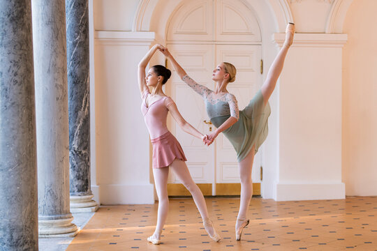Two young ballerina girls doing pointe dance in a park pavilion