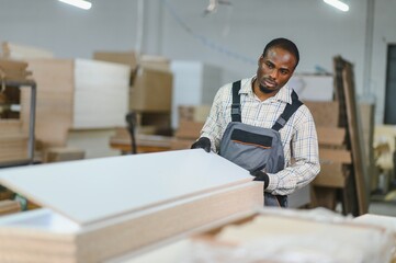Carpenter moving wooden boards in furniture factory