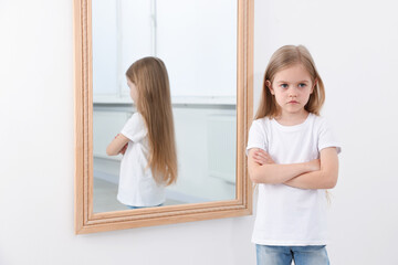 Upset little girl near mirror at home