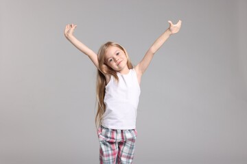 Cute little girl in pajamas on grey background