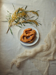 Plate of Frisjoli – Sardinian Carnival Fritters with Mimosa and Cashmere Scarf, Vertical Flat Lay 