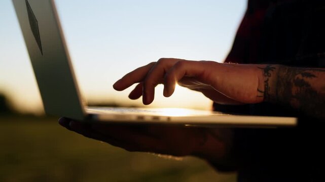 Closeup of farmer hands typing on laptop in agricultural field in summer day. Modern technology for agribusiness, innovation and business in agricultural area, agronomist use internet for planning