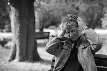 Homeless man on bench in park, space for text. Black and white effect