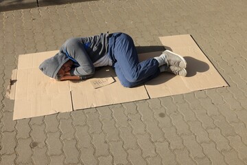 Homeless man sleeping on carton and sign Help outdoors