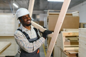 Skilled worker carrying wooden planks in factory