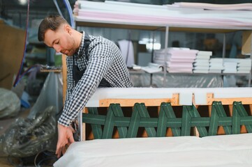 Carpenter working on sofa frame in furniture factory